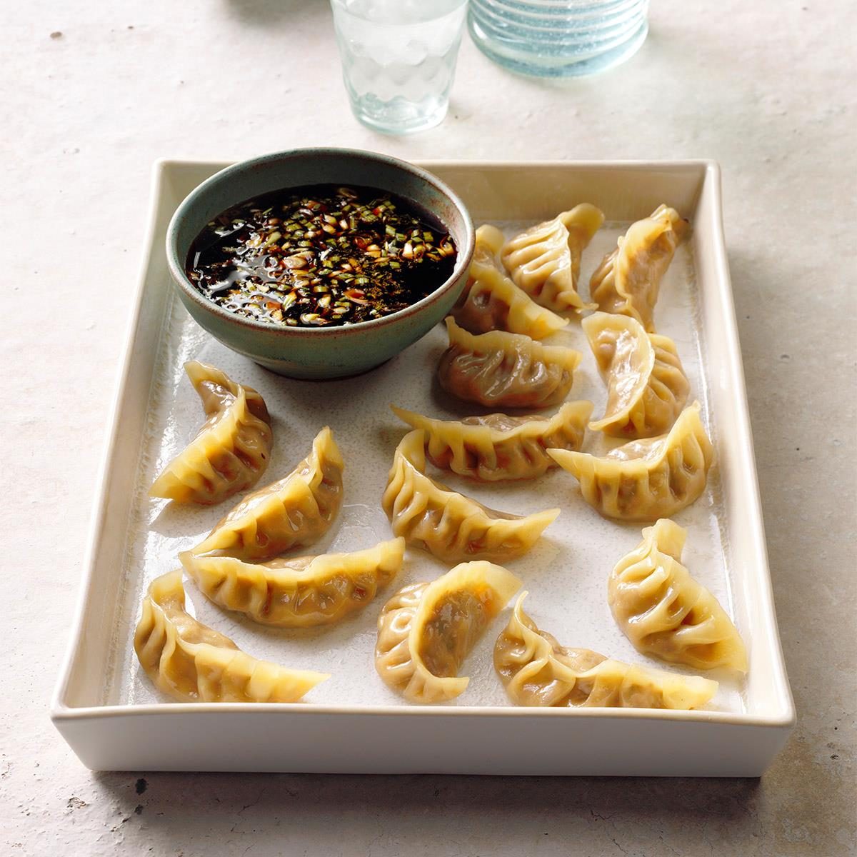 A tray of chicken pot stickers with dipping sauce.